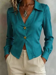 Detail shot of a teal long-sleeve blouse with stylish V-neck and golden decorative buttons.