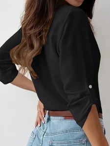 Detail view of a black women's lapel shirt with metal buttons on roll-up sleeves.