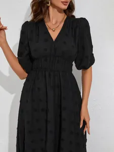 Detailed view of black V-neck dress featuring puff sleeves and textured swiss dots