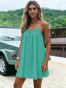 Modèle portant la mini-robe plissée turquoise dans un décor de vacances avec voiture ancienne