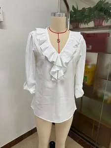 Vooraanzicht van een witte blouse met lange mouwen, V-hals en ruches op een paspop.
