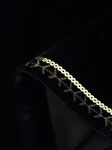 Macro di gilet in velluto nero con paillettes dorate e ricami in oro intricati.
