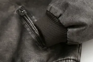 Dettaglio del polsino a coste e della tasca con zip su una giacca in ecopelle.