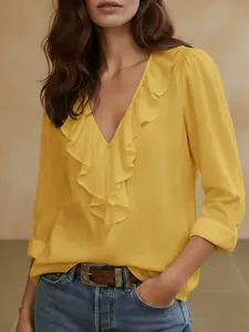 Detail van een gele blouse met V-hals, elegante ruches en lange mouwen voor dames.