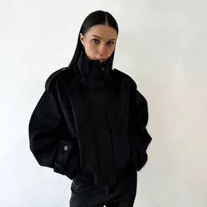 Detailed view of black wool coat with high stand collar and shoulder epaulettes on model