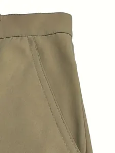 Close-up detail of khaki cotton shorts showing waistband and double-stitched pocket.