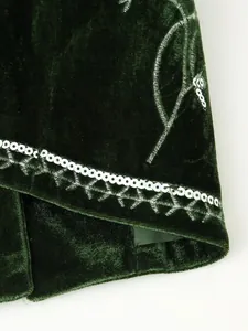 Dettaglio ravvicinato di un gilet in velluto verde scuro con paillettes e ricami fogliari