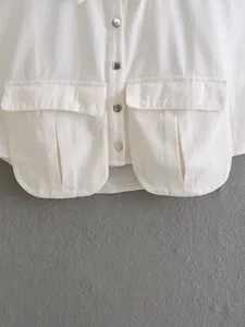 Detailed view of a white denim jacket featuring large pleated pockets and snap buttons