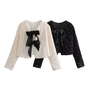 Detailed view of cream and black sequined cropped jackets with elegant front bow ties
