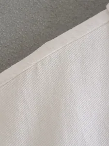 Close-up of white denim fabric texture with clean seam detail on casual jacket