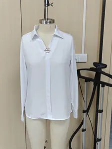 Detalle de una camisa blanca de manga larga con cierre de perla