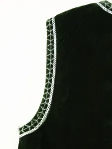 Primo piano dettagliato con paillettes argentate e ricami su un gilet in velluto verde scuro