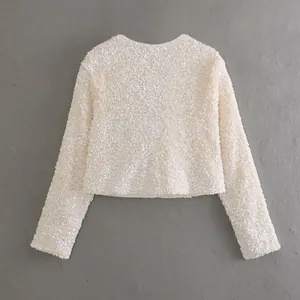 Detailed view of a white sequin cropped jacket featuring long sleeves and round neck design