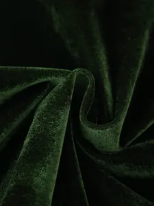 Primo piano del lussuoso tessuto di velluto verde scuro con elegante drappeggio e lucentezza.