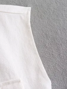 Close-up of high-quality white denim fabric and stitching on a casual cropped vest