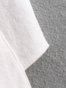Macro view of the white denim fabric texture and neat stitching on the hem.