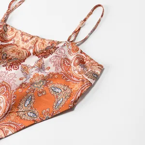 Macro detail of retro paisley print on orange satin halter top showing fine fabric texture