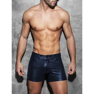 Men's sexy navy blue PU leather slim fit shorts shown from the front on a concrete wall