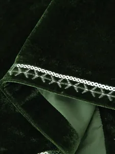 Dettaglio ravvicinato di un gilet in velluto verde scuro con paillettes e ricami d'argento