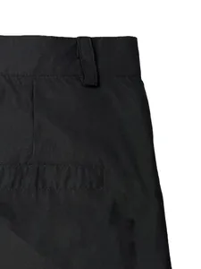 Close-up detail of black cotton shorts showing waistband stitching and pocket construction.