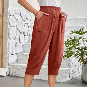 Detail view of rusty-red linen cropped pants with elastic waist and large pockets
