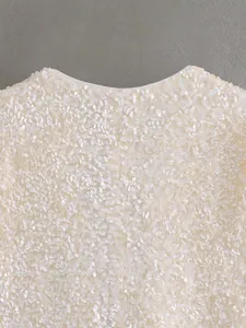 Close-up detail of white sequin jacket showing dense embroidery and round neckline design.