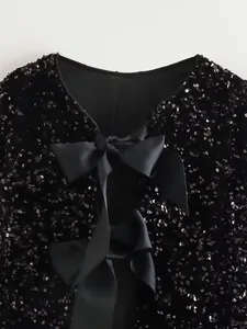 Detailed back view of a black sequined jacket featuring elegant ribbon bow ties.
