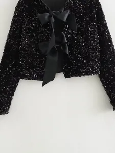 Macro view of sparkly black sequin fabric and elegant satin bow closures on jacket