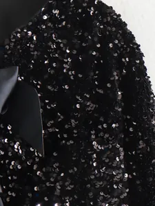 Detailed macro view of sparkling black sequins and large satin bow on party jacket