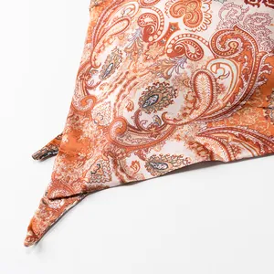 Macro detail of vintage orange paisley print on smooth satin fabric.