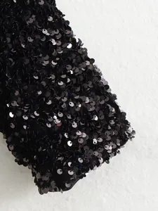 Close-up macro detail showing the dense black shimmering sequins on the sleeve of a jacket.