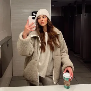 Detail view of an oversized beige sherpa fleece jacket on a model in a cozy winter outfit