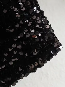 Detailed macro view of the shimmering black sequins on this trendy nightclub jacket.