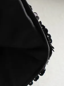 Macro detail of a black sequined jacket showing the inner lining and zipper closure