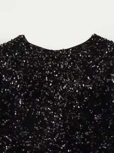 Detailed view of the black sequined round neckline on a glamorous evening party jacket