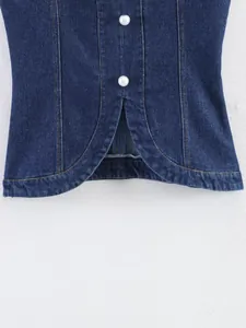 Vue détaillée d'un gilet en jean bleu avec boutons nacrés et fente à l'ourlet du bas