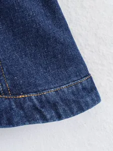 Gros plan de la texture du denim et des surpiqûres orange sur l'ourlet d'un haut