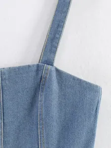 Gros plan détaillé d'une bretelle de caraco en jean bleu clair et de ses coutures.