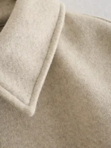 Detailaufnahme von strukturiertem Wollmischgewebe und Kragen eines modischen Wintermantels