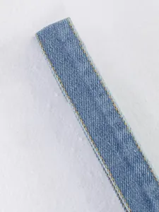 Gros plan détaillé de la sangle de gilet en denim bleu avec surpiqûres jaunes contrastées