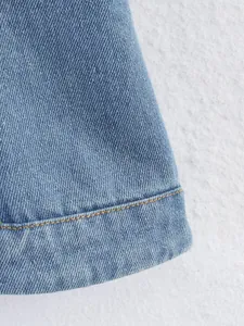 Vue détaillée de l'ourlet d'un débardeur en jean bleu avec coutures contrastées.