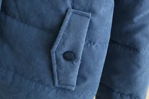 Close-up detail of a blue padded puffer jacket featuring a pocket with snap button closure