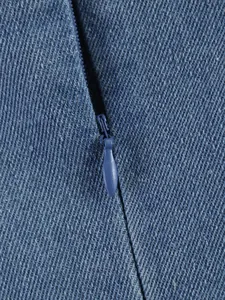 Gros plan détaillé du tissu denim bleu et fermeture éclair cachée sur un haut sans manches.