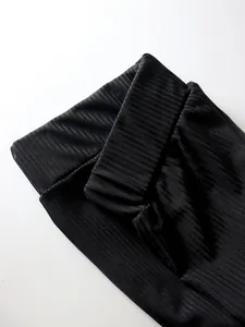 Close-up of black ribbed fabric and high waistband on slim fit flare trousers