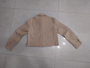 Vista posteriore di una giacca corta in lana morbida beige con colletto a rever