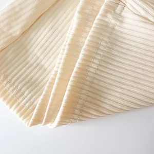 Macro detail showing the cream ribbed fabric texture and fine stitching of these pants