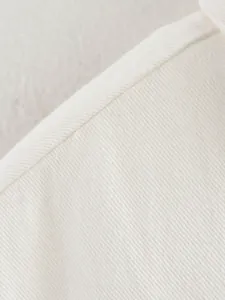 Macro shot of white faux denim fabric texture with clean seam stitching details.