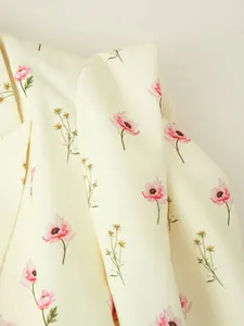 Vue détaillée de l'imprimé floral rose et jaune délicat sur le tissu du blazer crème