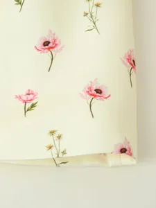Détail en gros plan du tissu crème avec un imprimé floral rose délicat sur le blazer.