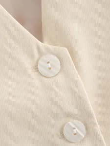 Detailed close-up of pearlescent buttons and textured twill fabric on beige women's vest